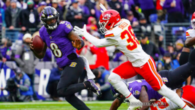 Baltimore Ravens quarterback Lamar Jackson (L) scrambles for yardage while elduding a tackle by Kansas City Chiefs cornerback L'Jarius Sneed (R) during the first half of the AFC
