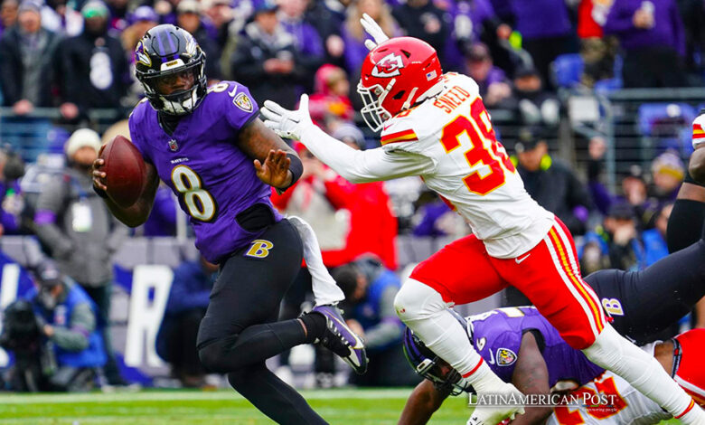 Baltimore Ravens quarterback Lamar Jackson (L) scrambles for yardage while elduding a tackle by Kansas City Chiefs cornerback L'Jarius Sneed (R) during the first half of the AFC