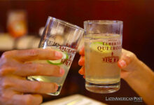 Una pareja brinda con dos vasos de "Chilcano" elaborado con pisco en el antiguo bar "Queirolo"