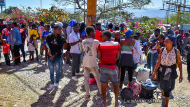 Personas esperan en una vía con sus pertenencias hoy, en Puerto Príncipe (Haití)