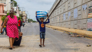 Una mujer y un niño junto caminan con sus pertenencias después de un ataque de bandas armadas en el sector de Delmas 22 este jueves, en Puerto Príncipe (Haití).