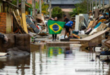Una mujer sostiene una bandera de Brasil en medio de una calle afectada por las inundaciones, este lunes en Porto Alegre