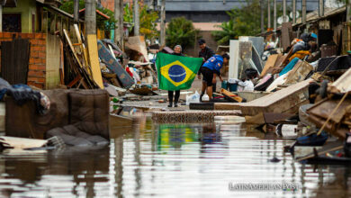 Una mujer sostiene una bandera de Brasil en medio de una calle afectada por las inundaciones, este lunes en Porto Alegre