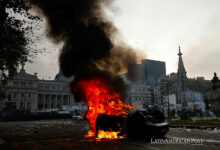 Fotografía de un auto quemado durante enfrentamientos entre la policía y personas que protestan a las afueras del senado durante un debate este miércoles, en Buenos Aires (Argentina).