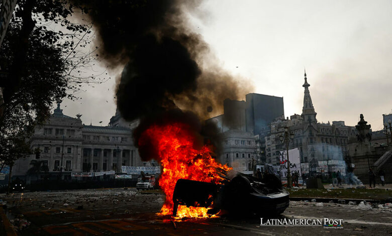 Fotografía de un auto quemado durante enfrentamientos entre la policía y personas que protestan a las afueras del senado durante un debate este miércoles, en Buenos Aires (Argentina).