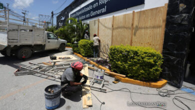 Trabajadores colocan tablas de madera para proteger un establecimiento por el paso del huracán Beryl, este miércoles en Cancún (México).