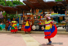 Una mujer con traje típico camina frente a puestos de artesanías este sábado, antes de la llegada de los duques de Sussex, el príncipe Enrique y Meghan, a San Basilio de Palenque (Colombia).