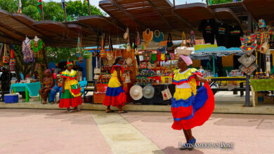 Una mujer con traje típico camina frente a puestos de artesanías este sábado, antes de la llegada de los duques de Sussex, el príncipe Enrique y Meghan, a San Basilio de Palenque (Colombia).