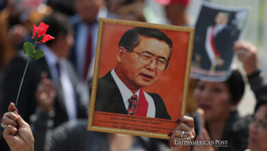 Simpatizantes del fallecido expresidente de Perú Alberto Fujimori sostienen retratos de Fujimori en una fila para asistir a su velatorio este jueves, en Lima (Perú).